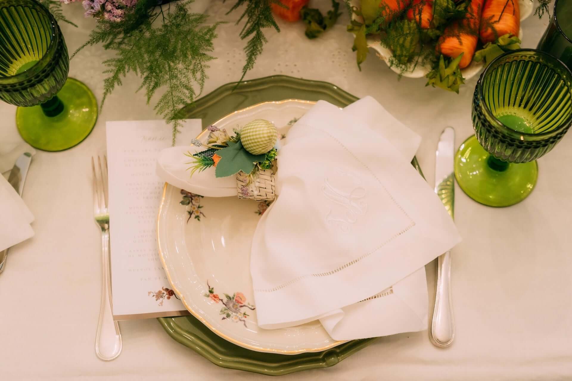 Green charger plate layered below floral printed dinner plate and dinner napkin