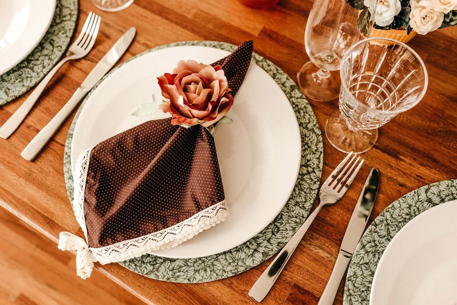 Table setting with lace patterned napkin ring, dinner plate, and charger plate