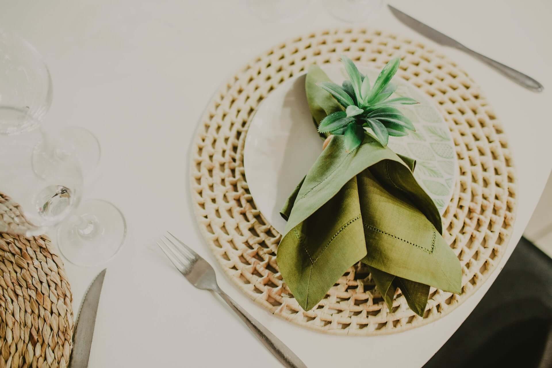 Green dinner napkin over dinner plate and wicker placemat