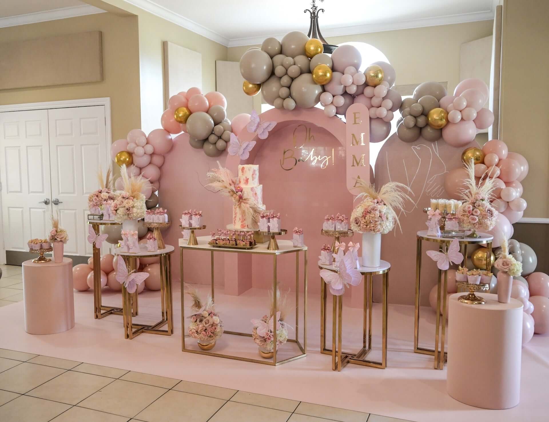 Pink and gold birthday setup with pedestals and backdrops